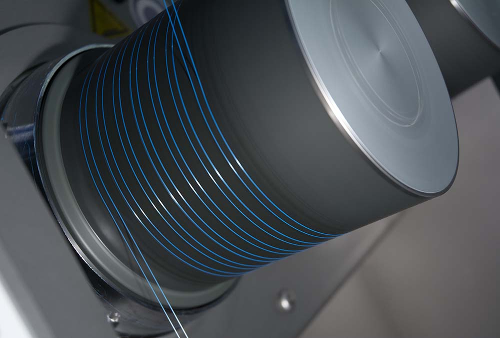 A multifilament yarn being heated and drawn over ceramic coated godet roller.